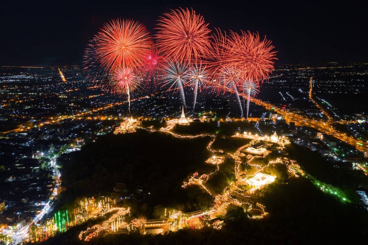 Aerial view of a festive night scene with bright fireworks above a lit hill, surrounded by a twAerial view of a festive night scene with bright fireworks above a lit hill, surrounded by a twinkling cityscape.inkling cityscape.