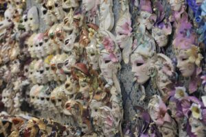 A colorful assortment of ornate masks displayed against a patterned backdrop, showcasing intricate designs and embellishments.