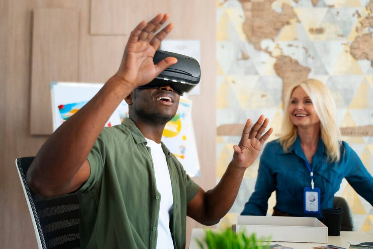 A person wearing a VR headset gestures excitedly while another woman observes attentively in a modern office setting.