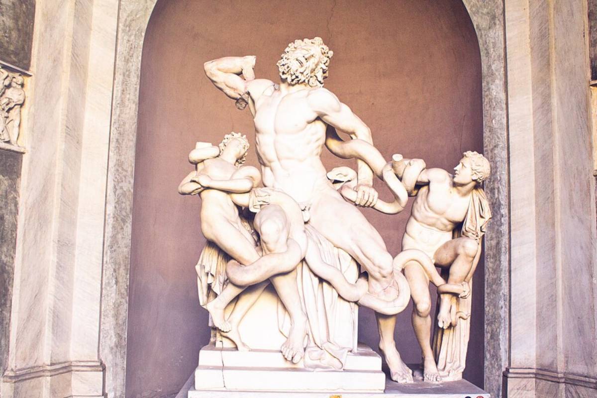 A dynamic marble sculpture depicting a muscular figure battling serpents, surrounded by two figures entwined with the snakes.